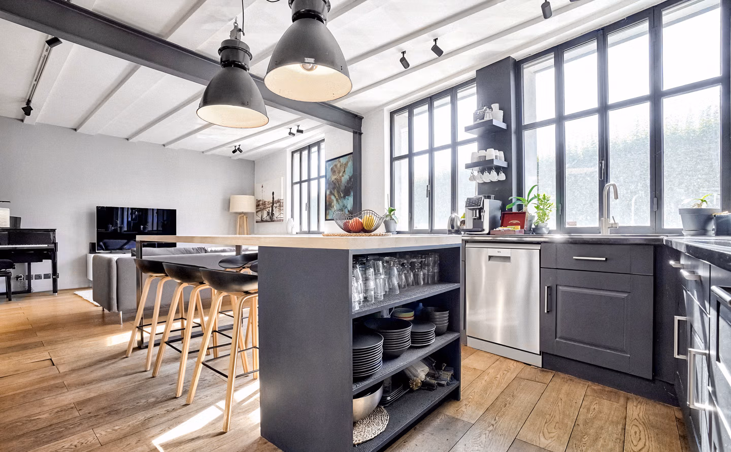 Cuisine ouverte contemporaine meubles bois naturel, mur briques blanches, luminaires variés suspension sphérique et spots laiton, verrière noire, plan travail marbre blanc, miroir rond bois, plantes suspendues Cuisine ouverte contemporaine meubles bois naturel, mur briques blanches, luminaires variés suspension sphérique et spots laiton, verrière noire, plan travail marbre blanc, miroir rond bois, plantes suspendues