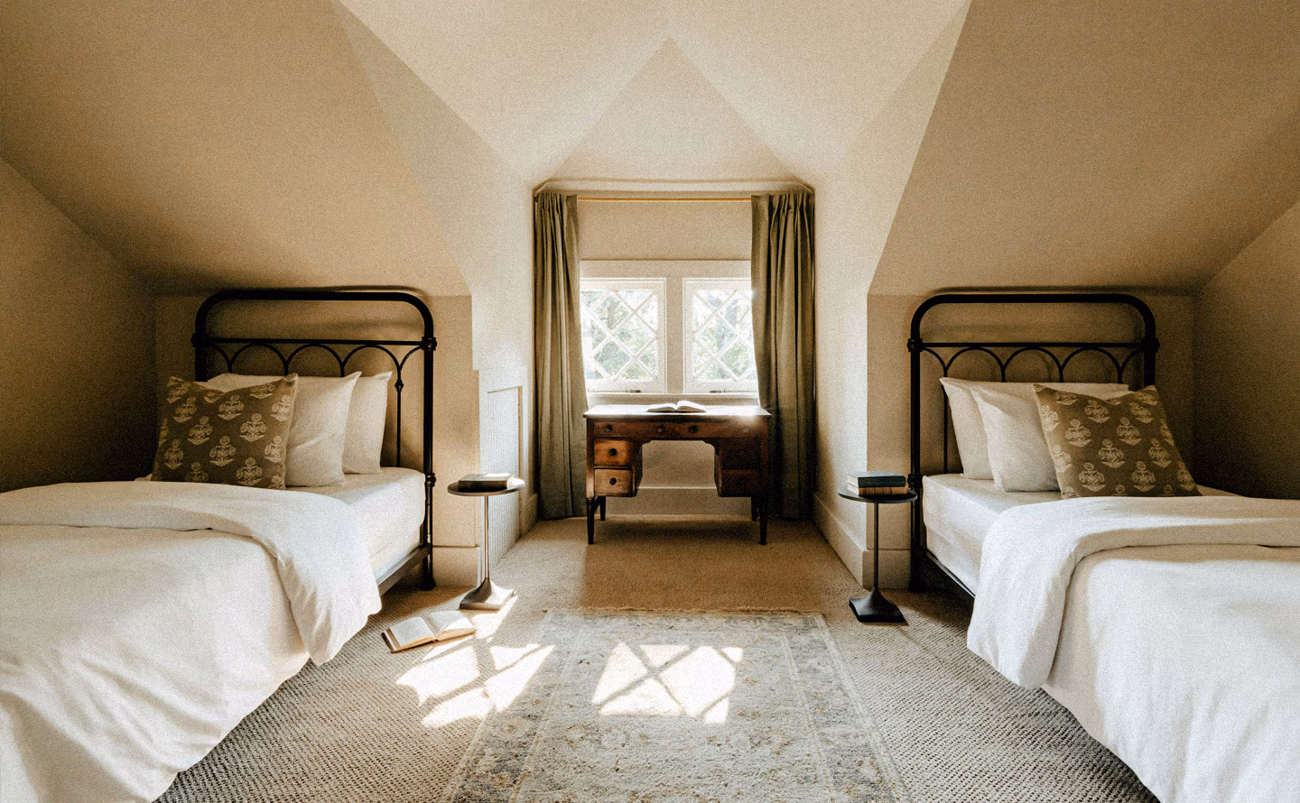 Chambre mansardée lits jumeaux fer noir extra-longs, linges blancs coussins imprimés beiges, bureau ancien bois fenêtre croisillons centrale, tables chevet rondes noires, tapis naturel sisal, plafond voûté blanc, symétrie parfaite Chambre mansardée lits jumeaux fer noir extra-longs, linges blancs coussins imprimés beiges, bureau ancien bois fenêtre croisillons centrale, tables chevet rondes noires, tapis naturel sisal, plafond voûté blanc, symétrie parfaite