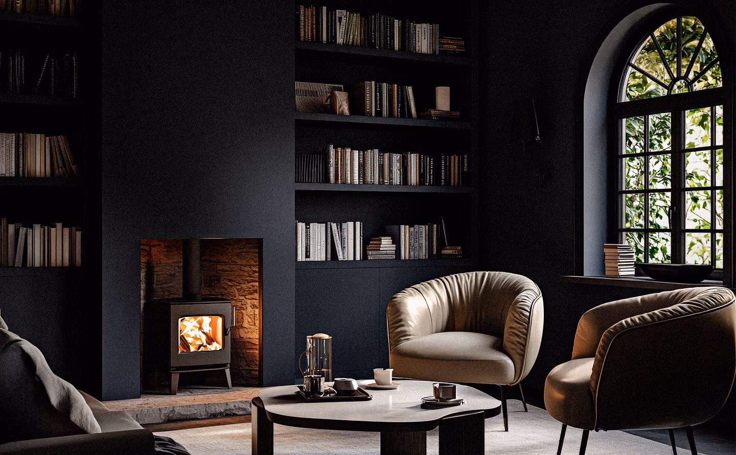 Salon cocooning aux murs noirs avec bibliothèque intégrée, fauteuils en cuir caramel capitonné, poêle à bois et grande fenêtre cintrée créant un espace snug anglais intimiste Salon cocooning aux murs noirs avec bibliothèque intégrée, fauteuils en cuir caramel capitonné, poêle à bois et grande fenêtre cintrée créant un espace snug anglais intimiste