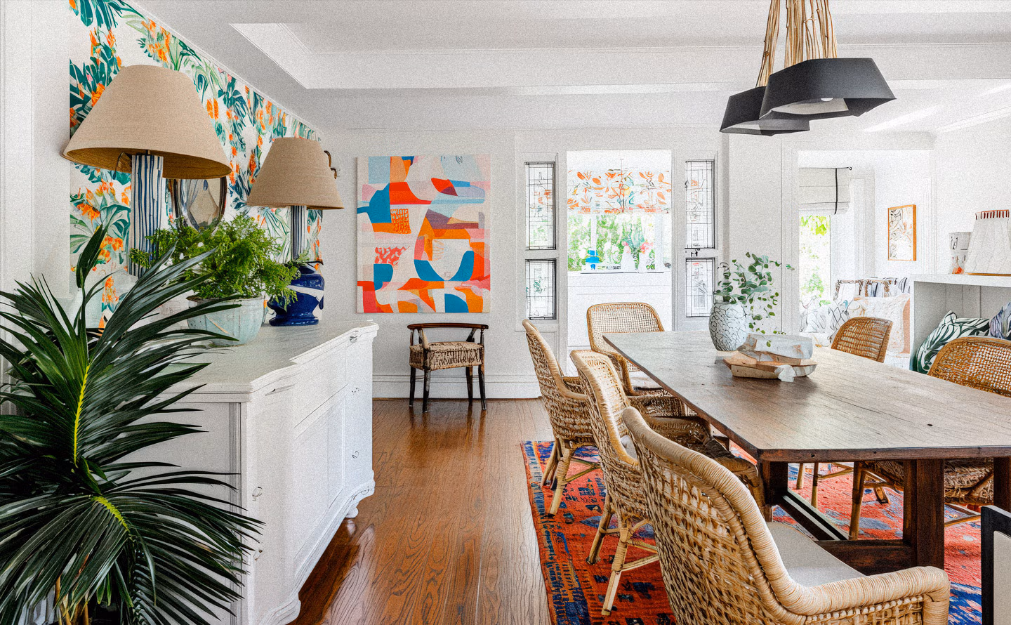 Salle à manger lumineuse avec papier peint tropical coloré, table bois massif, chaises en rotin naturel et tapis kilim géométrique illustrant l'équilibre sophistiqué entre motifs exubérants et matières apaisantes Salle à manger lumineuse avec papier peint tropical coloré, table bois massif, chaises en rotin naturel et tapis kilim géométrique illustrant l'équilibre sophistiqué entre motifs exubérants et matières apaisantes