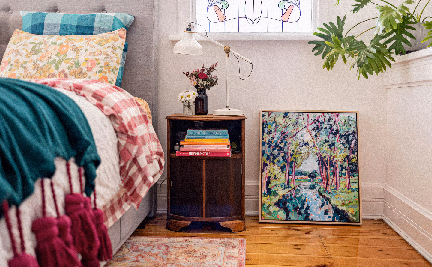 Chambre éclectique aux murs beige rosé avec lit literie colorée turquoise et motifs floraux vintage, meuble ancien bois sombre table de nuit chargé de livres design et lampe articulée, grande toile impressionniste colorée posée au sol et œuvres art nouveau au mur illustrant la stratification confortable de couleurs saturées et motifs multiples Chambre éclectique aux murs beige rosé avec lit literie colorée turquoise et motifs floraux vintage, meuble ancien bois sombre table de nuit chargé de livres design et lampe articulée, grande toile impressionniste colorée posée au sol et œuvres art nouveau au mur illustrant la stratification confortable de couleurs saturées et motifs multiples