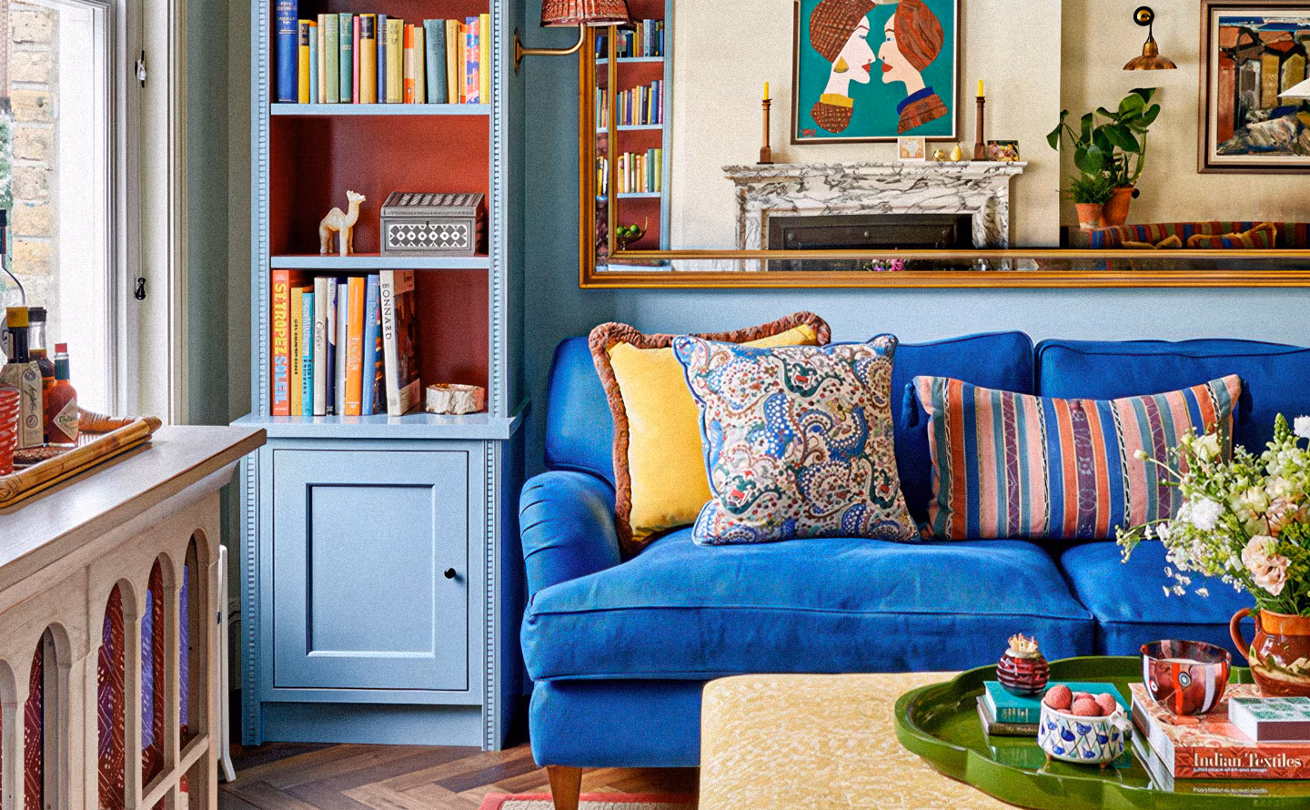 Salon maximaliste aux couleurs audacieuses avec canapé velours bleu électrique chargé de coussins jaune vif et motifs variés, bibliothèque bleue à fond rouge bordeaux remplie de livres colorés, grand miroir doré reflétant œuvre pop art turquoise, cheminée marbre blanc, pouf jaune pâle et table basse plateau vert illustrant le bleu comme dénominateur commun autorisant toutes les audaces chromatiques Salon maximaliste aux couleurs audacieuses avec canapé velours bleu électrique chargé de coussins jaune vif et motifs variés, bibliothèque bleue à fond rouge bordeaux remplie de livres colorés, grand miroir doré reflétant œuvre pop art turquoise, cheminée marbre blanc, pouf jaune pâle et table basse plateau vert illustrant le bleu comme dénominateur commun autorisant toutes les audaces chromatiques
