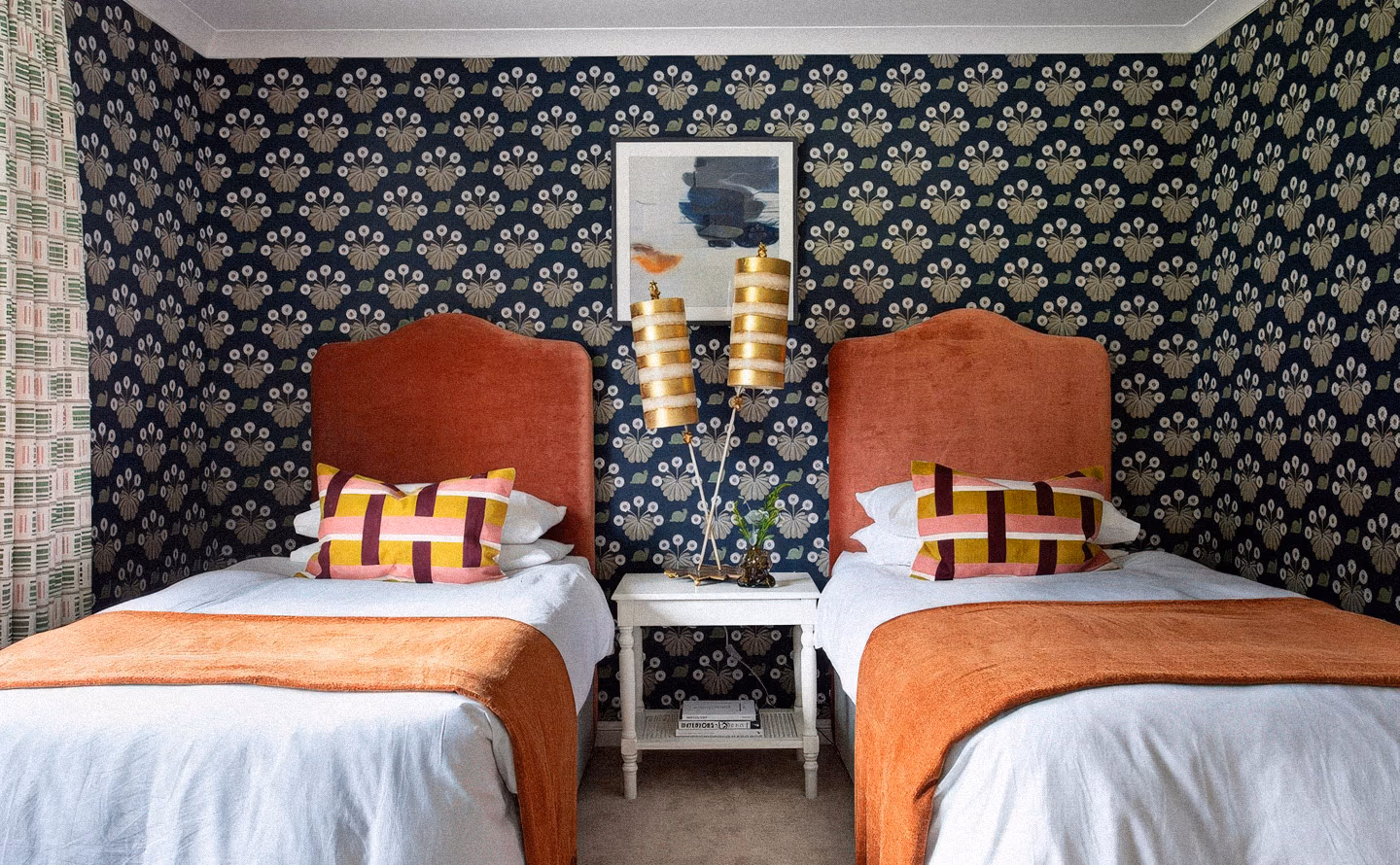 Chambre d'amis sophistiquée avec deux lits jumeaux têtes de lit velours terracotta rembourrées, papier peint noir à motifs floraux dorés répétés, literie blanche jetés rouille, coussins géométriques multicolores rose jaune bordeaux, lampes décoratives dorées blanches empilées et table de nuit blanche illustrant l'association audacieuse de motifs et couleurs saturées maintenant élégance et cohérence Chambre d'amis sophistiquée avec deux lits jumeaux têtes de lit velours terracotta rembourrées, papier peint noir à motifs floraux dorés répétés, literie blanche jetés rouille, coussins géométriques multicolores rose jaune bordeaux, lampes décoratives dorées blanches empilées et table de nuit blanche illustrant l'association audacieuse de motifs et couleurs saturées maintenant élégance et cohérence