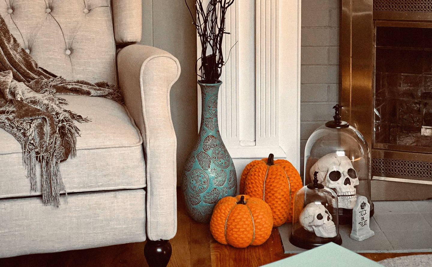 Coin salon automnal élégant mélangeant époques avec fauteuil beige capitonné recouvert de plaid franges, grand vase turquoise patiné à motifs dorés contenant branches séchées noires, citrouilles décoratives en velours orange texturé, crânes blancs sous cloche de verre et pierre tombale miniature RIP sur table basse, miroir ancien doré visible en arrière-plan illustrant la coexistence harmonieuse entre pièces vintage chinées et accessoires contemporains créant cette profondeur narrative impossible avec du neuf uniquement Coin salon automnal élégant mélangeant époques avec fauteuil beige capitonné recouvert de plaid franges, grand vase turquoise patiné à motifs dorés contenant branches séchées noires, citrouilles décoratives en velours orange texturé, crânes blancs sous cloche de verre et pierre tombale miniature RIP sur table basse, miroir ancien doré visible en arrière-plan illustrant la coexistence harmonieuse entre pièces vintage chinées et accessoires contemporains créant cette profondeur narrative impossible avec du neuf uniquement