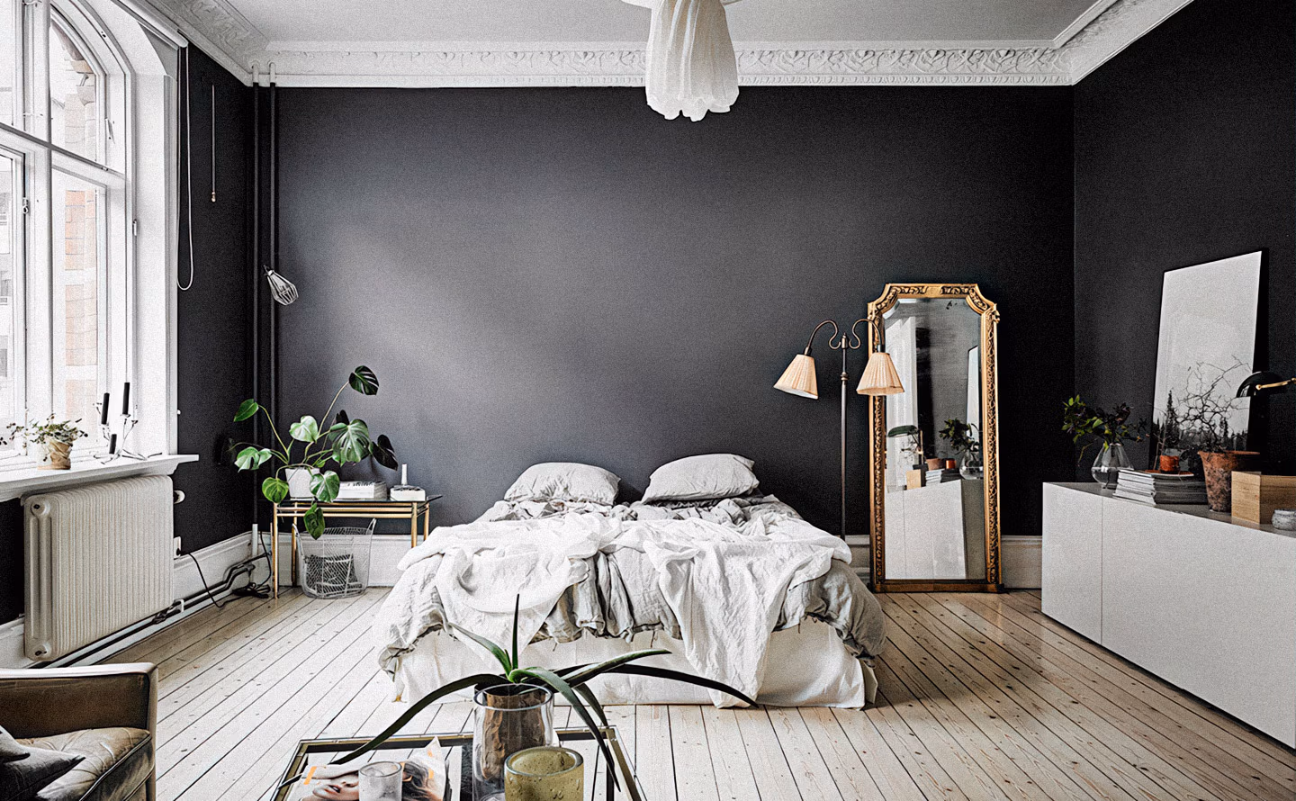 Chambre haussmannienne au mur d'accent noir anthracite profond contrastant avec moulures blanches du plafond et parquet blanchi, lit défait avec linge blanc, miroir baroque doré monumental, plantes vertes et lustre blanc suspendu illustrant qu'oser une teinte sombre saturée crée profondeur et sophistication impossibles avec tons clairs. Chambre haussmannienne au mur d'accent noir anthracite profond contrastant avec moulures blanches du plafond et parquet blanchi, lit défait avec linge blanc, miroir baroque doré monumental, plantes vertes et lustre blanc suspendu illustrant qu'oser une teinte sombre saturée crée profondeur et sophistication impossibles avec tons clairs.