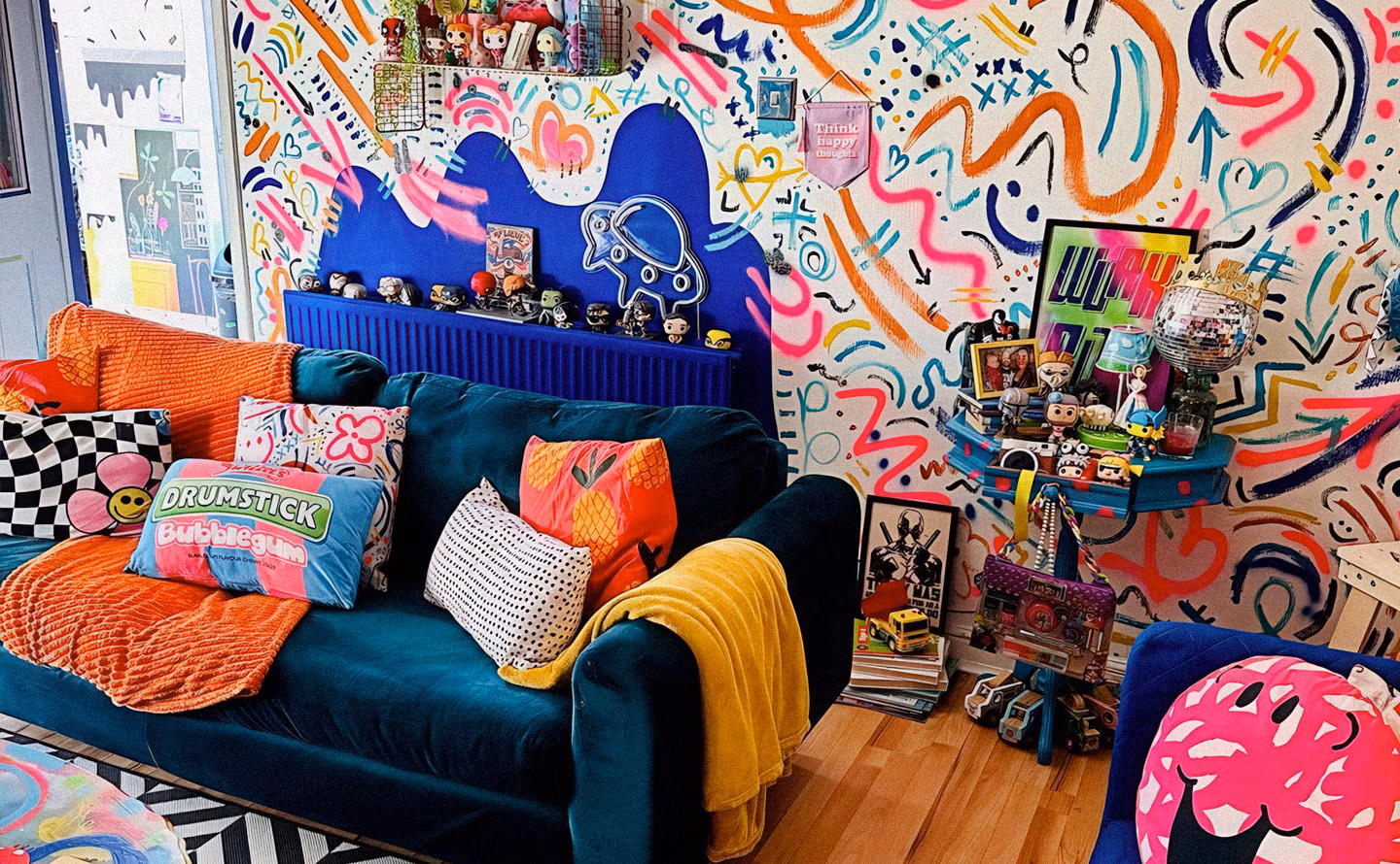 Salon maximalist exubérant avec mur entièrement recouvert de graffitis multicolores aux motifs graphiques, canapé bleu canard capitonné avec coussins orange et jaune vif, radiateur bleu électrique, collections de figurines pop culture exposées sur étagères turquoise, tapis damier noir et blanc, incarnant la philosophie de l'accumulation joyeuse d'objets aimés contre le minimalisme épuré. Salon maximalist exubérant avec mur entièrement recouvert de graffitis multicolores aux motifs graphiques, canapé bleu canard capitonné avec coussins orange et jaune vif, radiateur bleu électrique, collections de figurines pop culture exposées sur étagères turquoise, tapis damier noir et blanc, incarnant la philosophie de l'accumulation joyeuse d'objets aimés contre le minimalisme épuré.