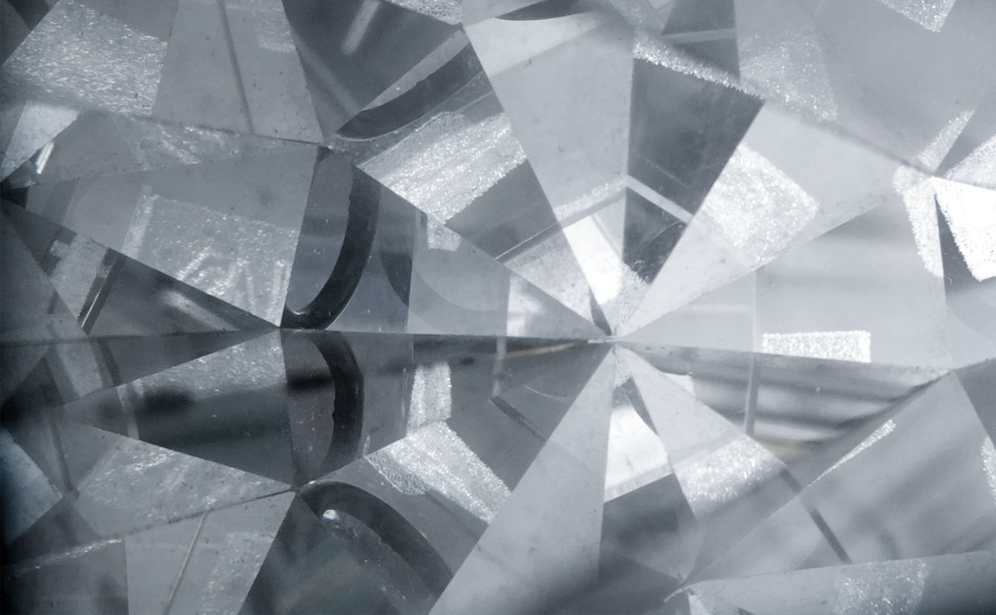 Vue macro des facettes d'un diamant taillé en brillant montrant la réfraction de la lumière à travers les plans cristallins et la précision géométrique de la taille