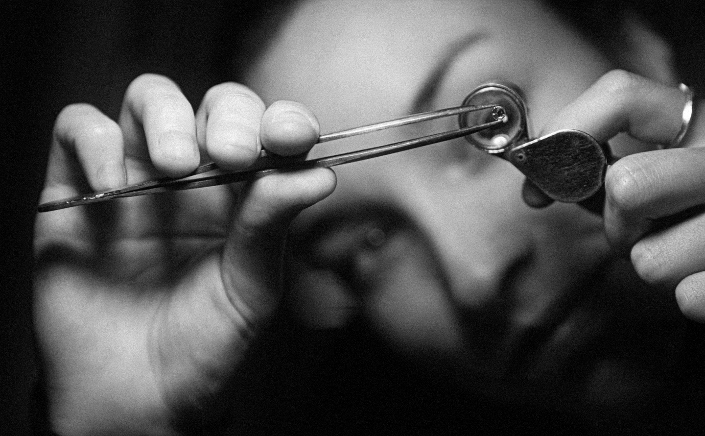 Gemmologue examinant un diamant à la loupe 10x pour évaluer sa pureté, ses inclusions et sa qualité avant certification professionnelle