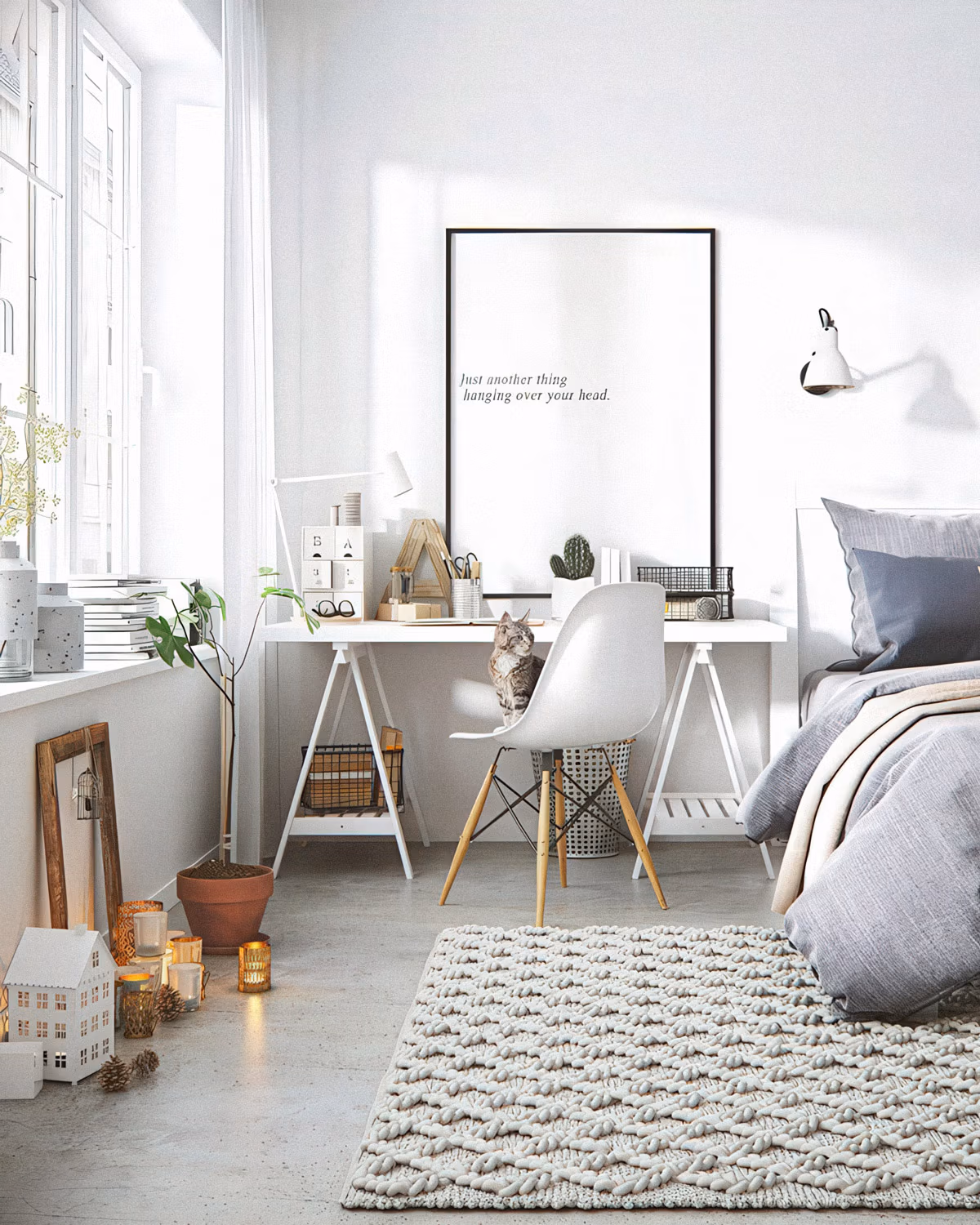 Chambre-bureau scandinave baignée de lumière naturelle avec bureau sur tréteaux blancs, chaise Eames DSW, lit habillé de lin gris-bleu, tapis en laine tressée écru, sol béton clair, plantes vertes, bougies et petits objets déco en bois créant une atmosphère hygge apaisante