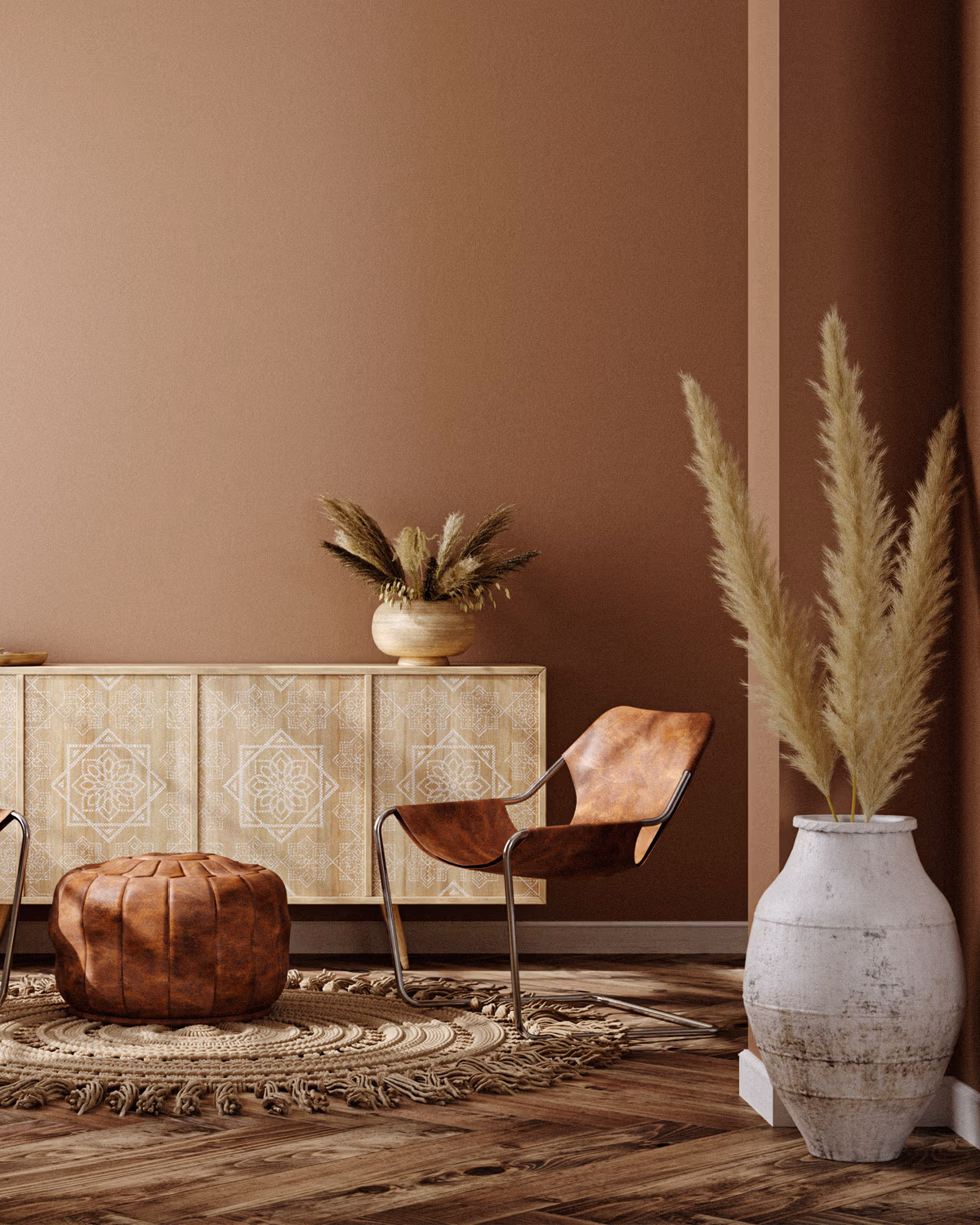Intérieur aux murs Mocha Mousse Pantone avec pouf marocain en cuir cognac, fauteuil design en cuir sur structure chromée tubulaire, buffet en bois clair orné de motifs géométriques ethniques, grand vase en céramique patinée avec herbes de la pampa et tapis rond en jute tressé sur parquet brut